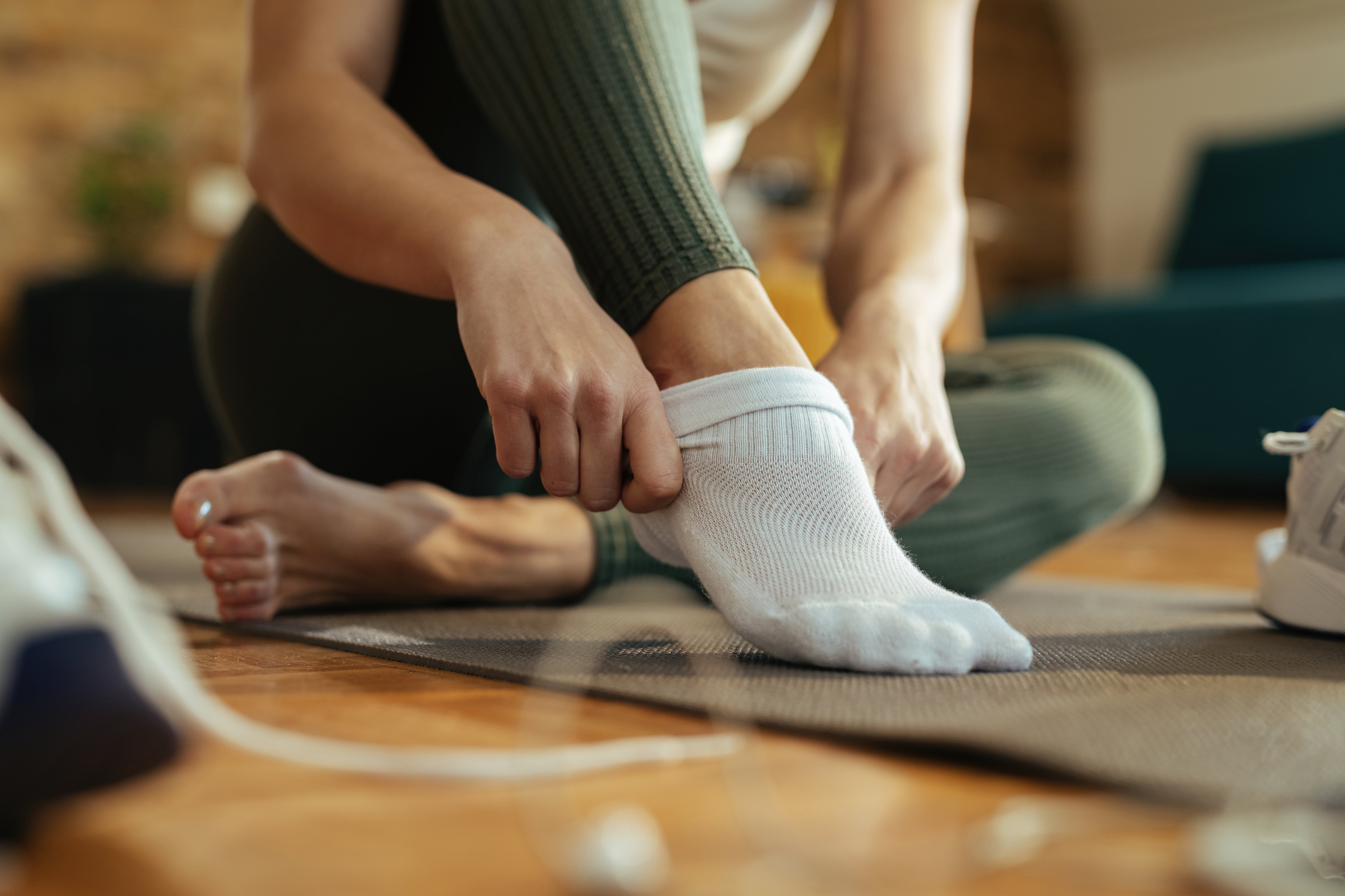Das Bild zeigt eine Frau mit Fokus auf den Füßen. Die Dame zieht sich Bambus Socken an.