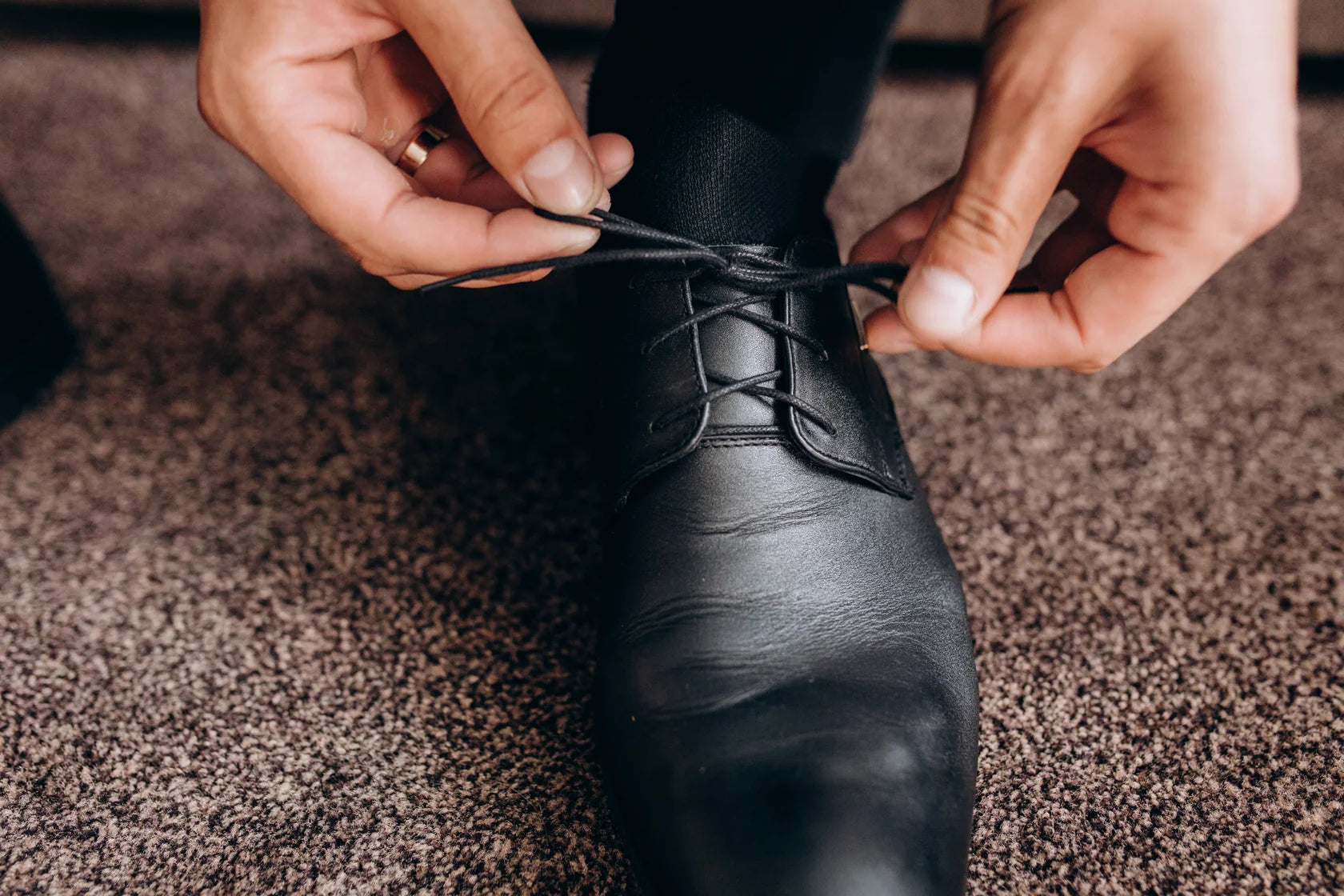 Businesssocken schwarz im Lederschuh – Mann bindet Schnürsenkel, glatte Spitze, eleganter Look